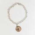 Silver chain bracelet with a gold fleur-de-lis charm on a white background