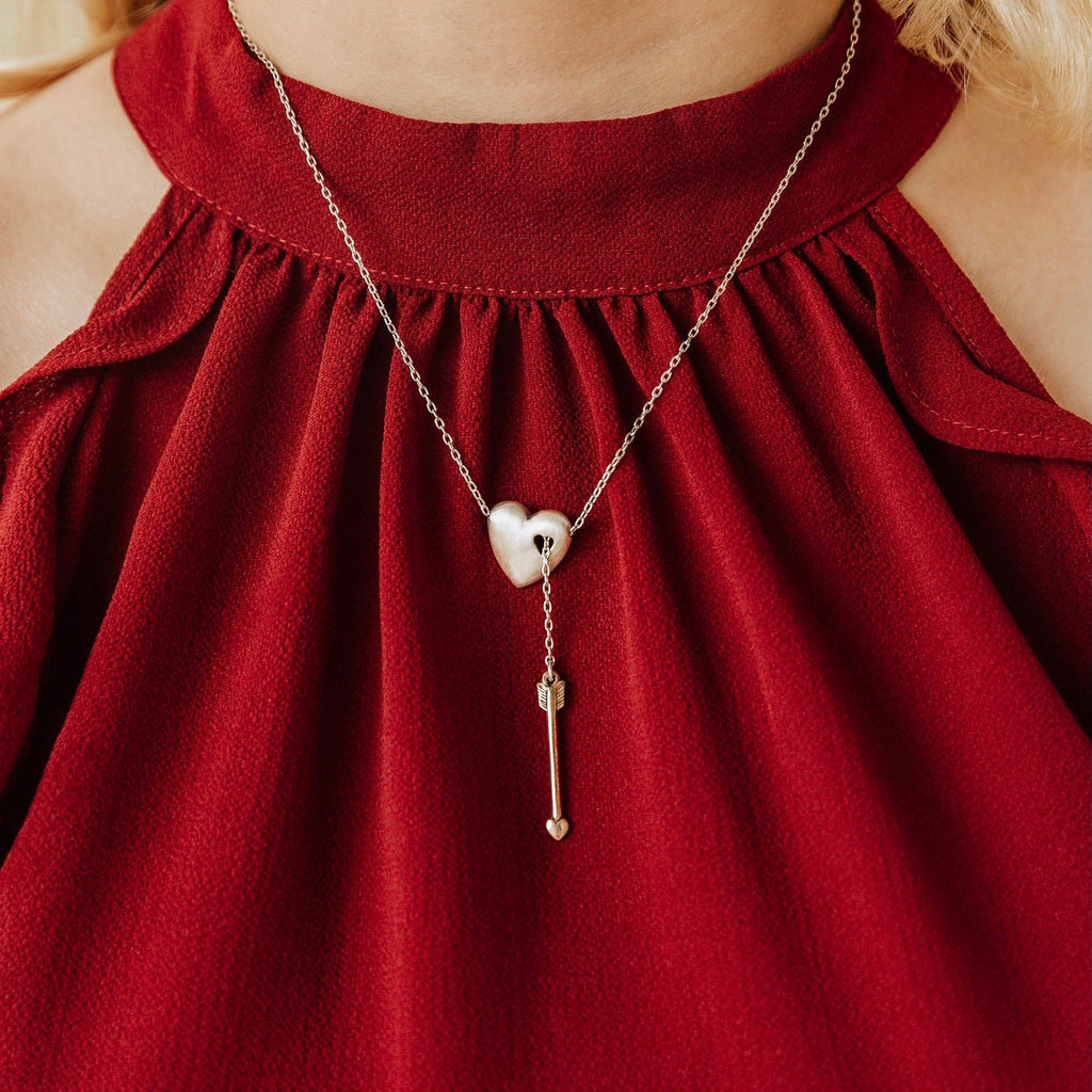 Woman wearing sterling silver heart and bronze arrow Y necklace inspired by Cupid