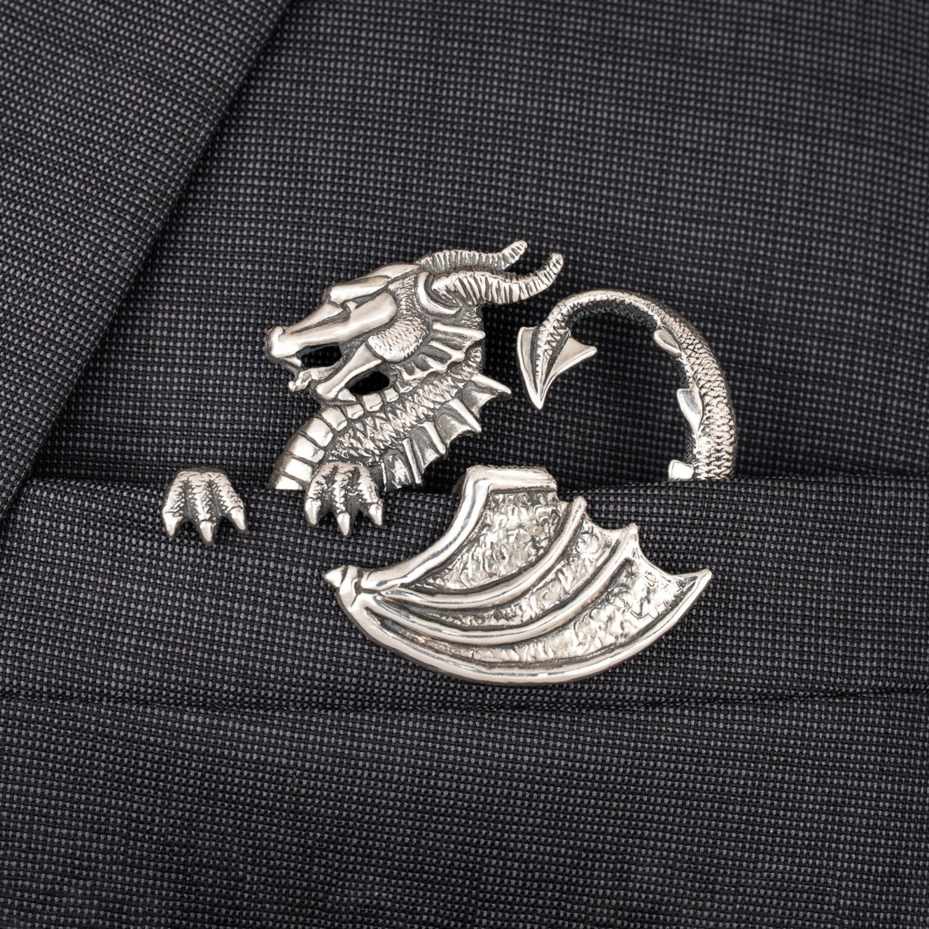 Silver dragon pocket square on a black fabric background