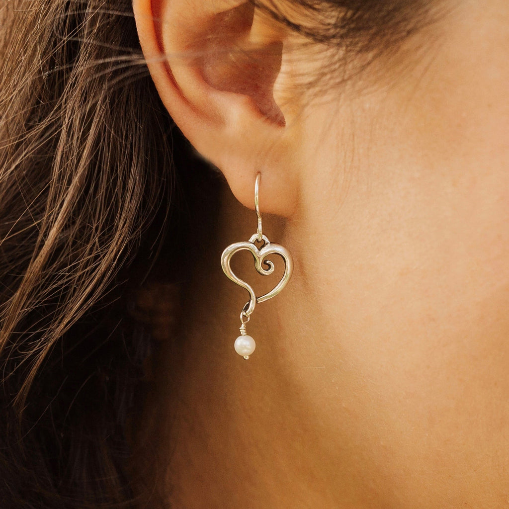 Woman wearing sterling silver heart pearl earrings