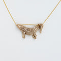 A gold-toned necklace featuring a textured alligator pendant on a delicate chain, photographed against a clean white background.