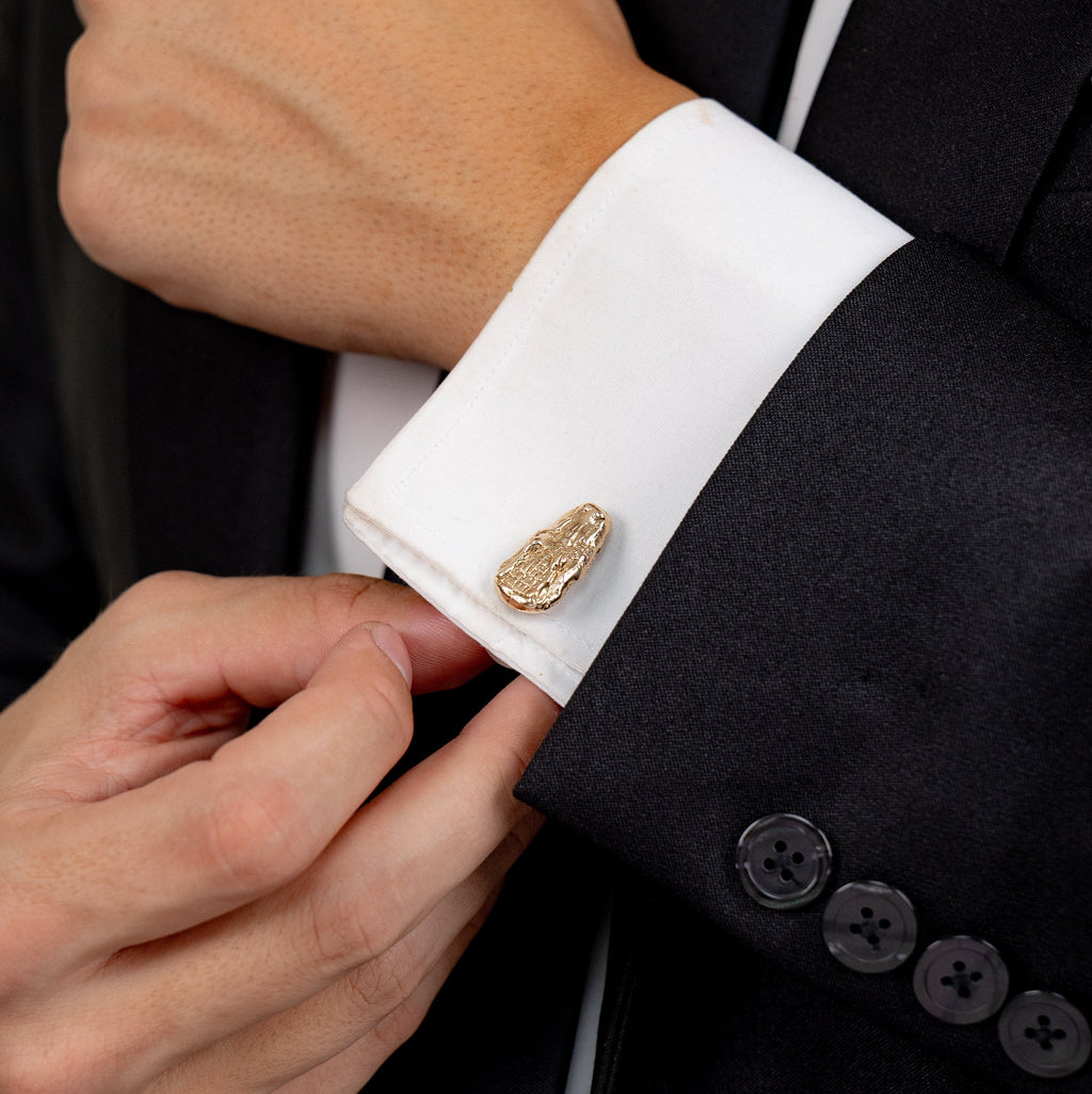 Gilded bronze alligator cufflinks worn on a white dress shirt cuff.