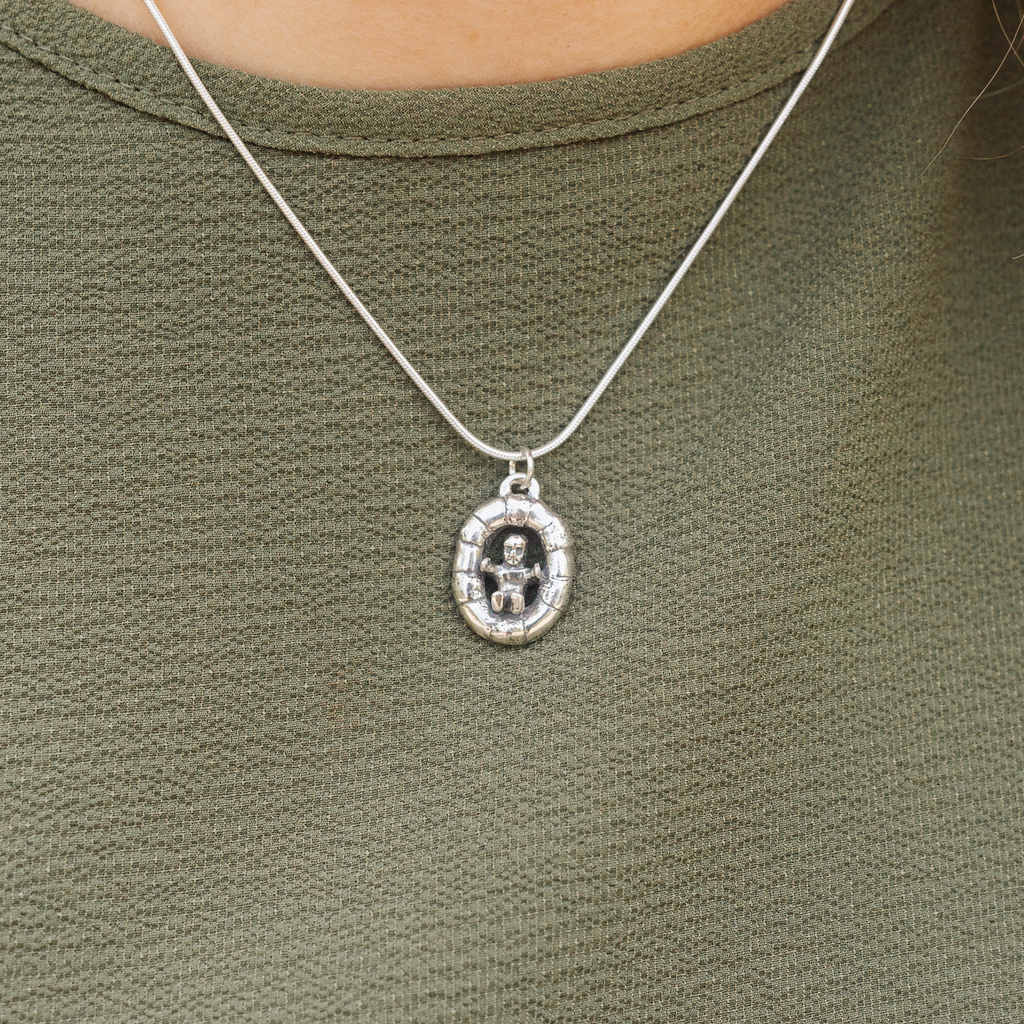 Close up of woman wearing Baby in King Cake sterling silver necklace inspired by Mardi Gras