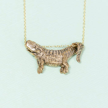 a gold necklace with a small crocodile pendant