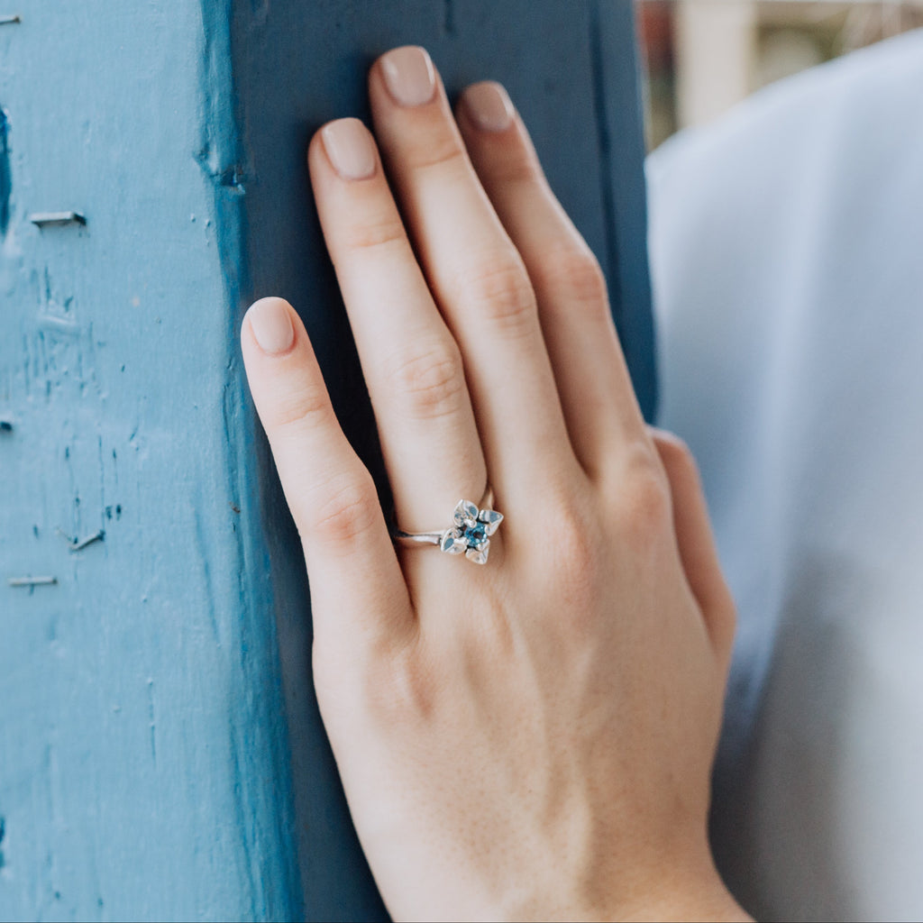 woman wearing blue topaz flower ring in sterling silver floral design