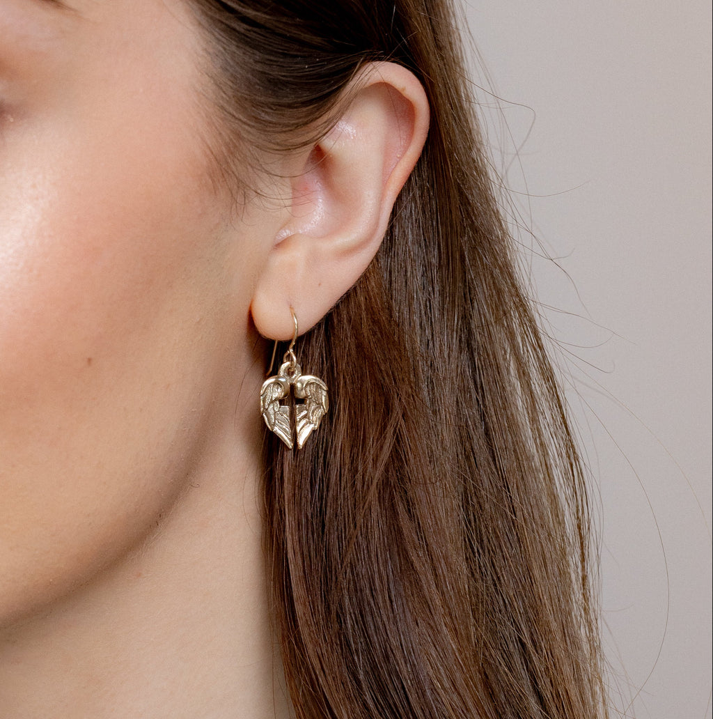 side view of bronze angel wing cross earrings on ear
