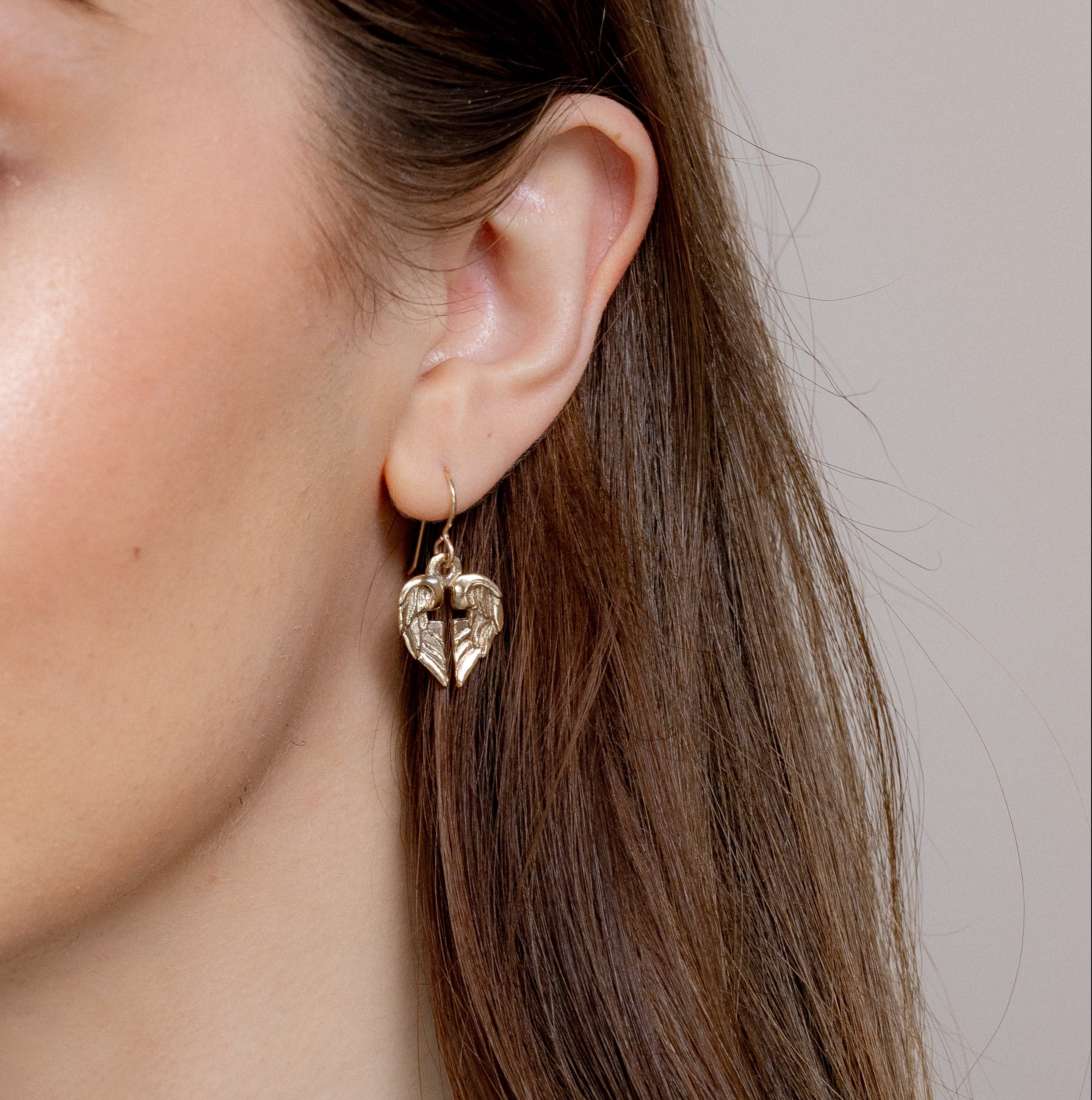 side view of bronze angel wing cross earrings on ear