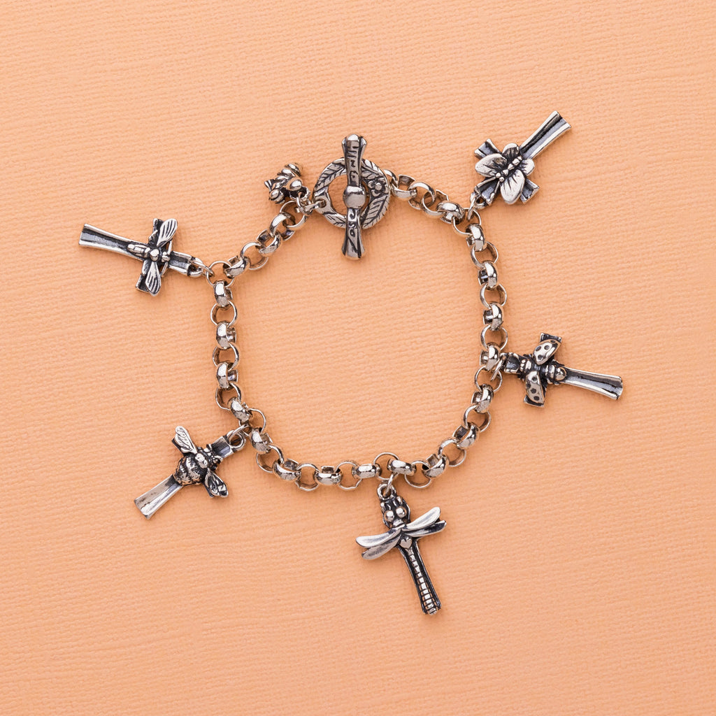  insect and cross charm bracelet styled on orange background showing detailed bug charms and toggle clasp