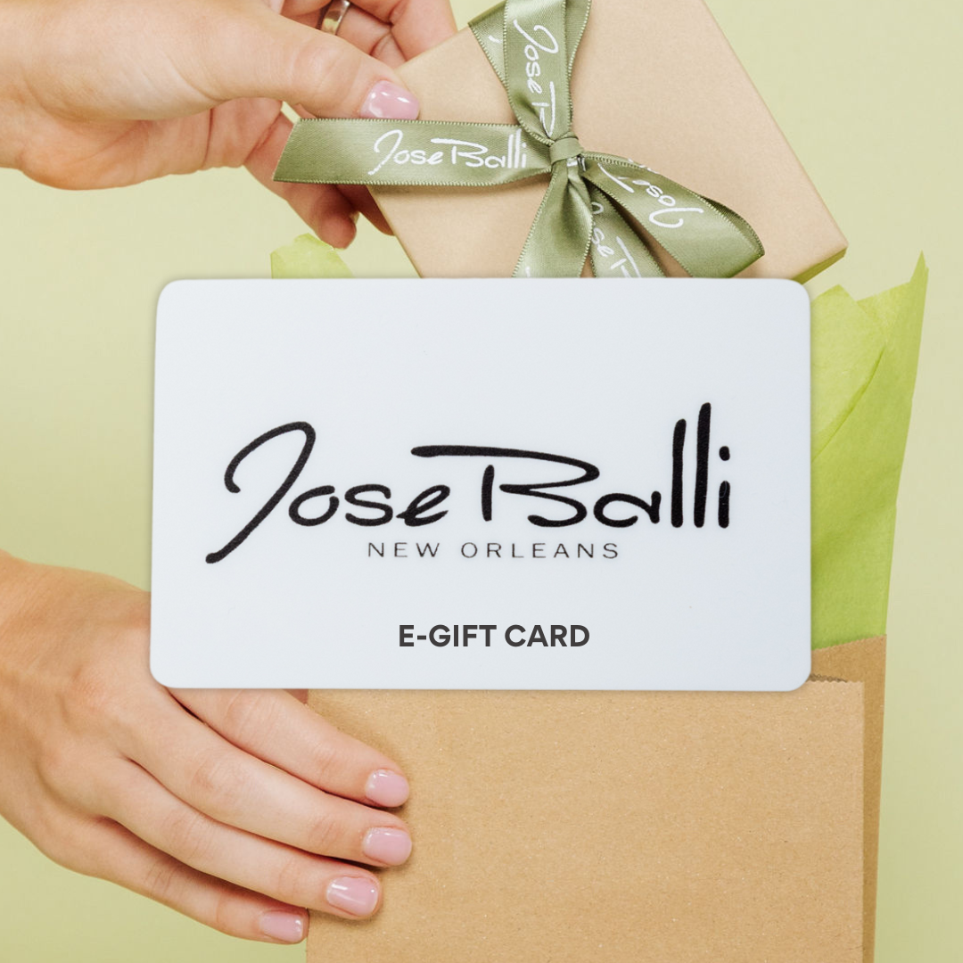 Woman holding a Jose Balli Jewelry e-gift card and gift bag, a New Orleans–inspired jewelry gift option with instant email delivery.