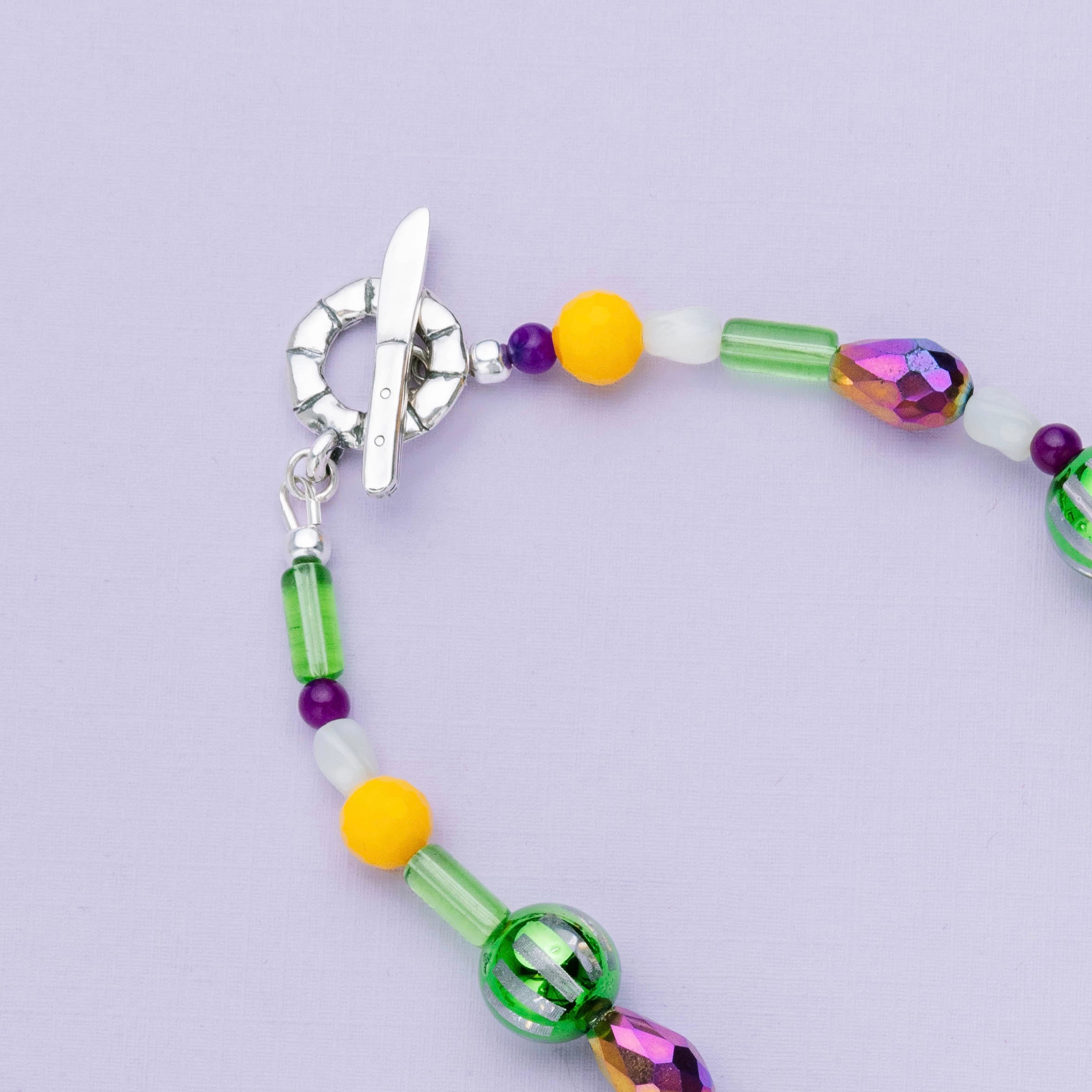 Detail of Mardi Gras Throw Necklace featuring king cake and knife toggle clasp