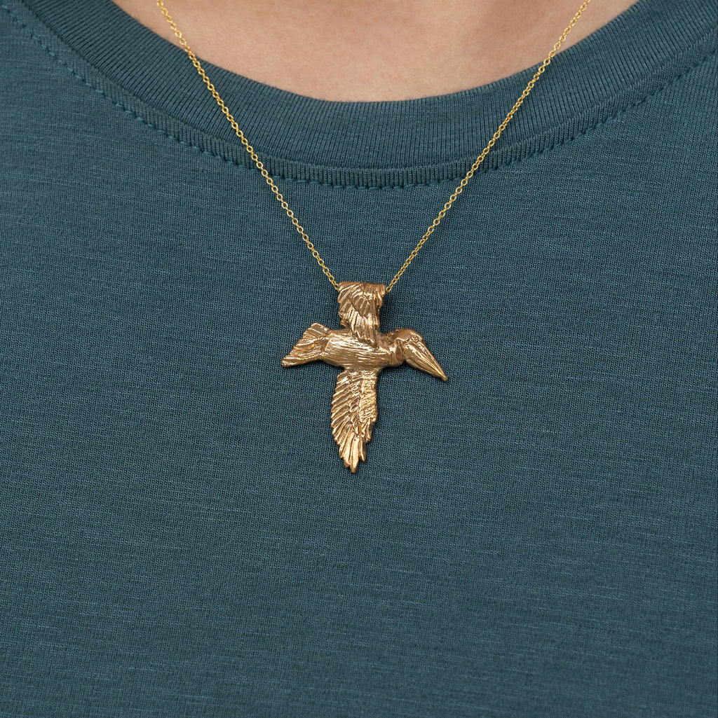 Bronze pelican cross necklace worn on model