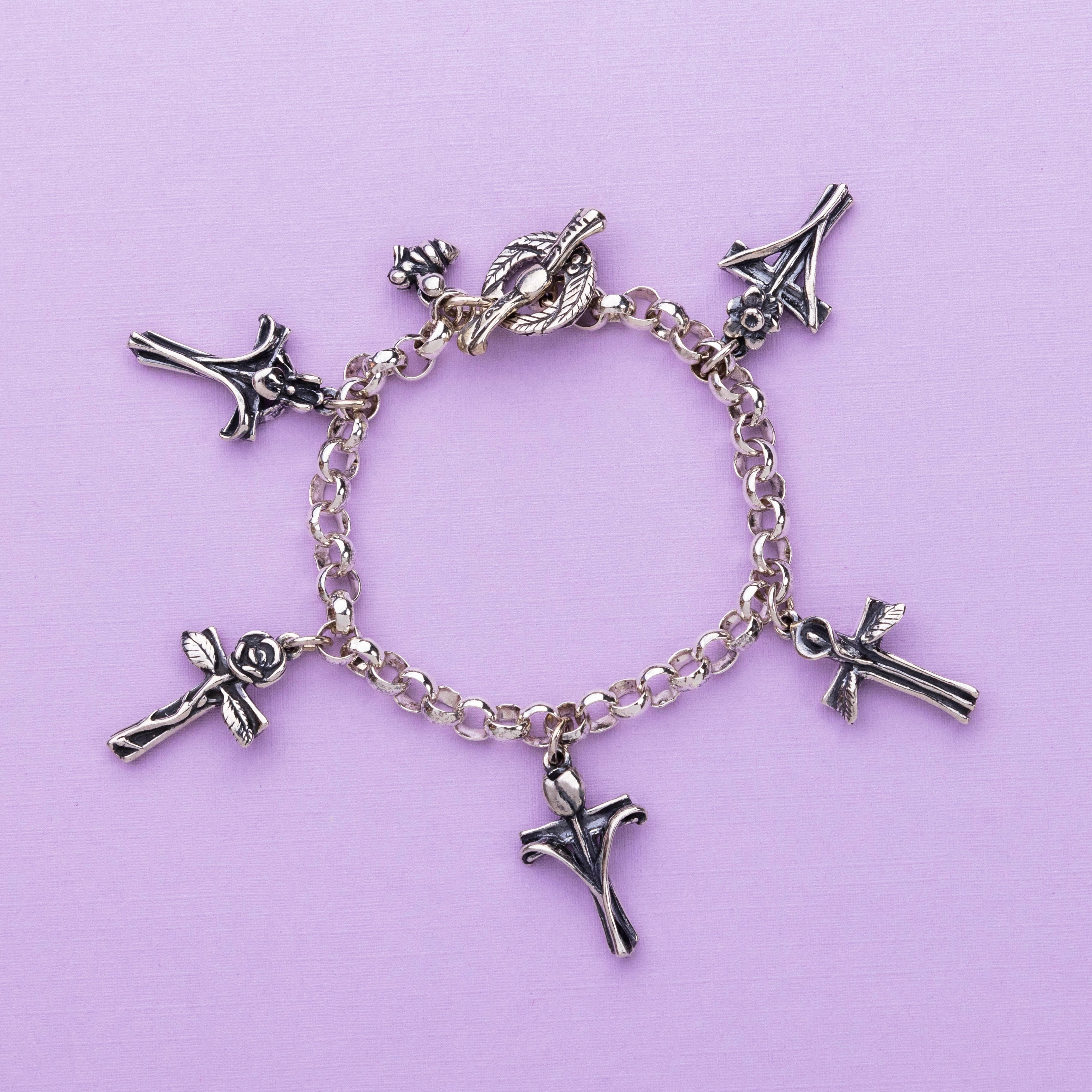 petals and prayers charm bracelet sterling silver cross flower bracelet flat lay detail close up 