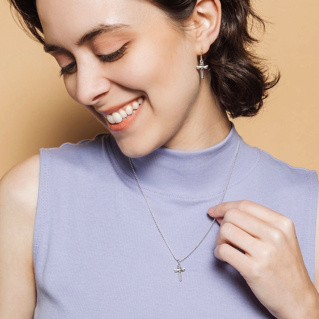 Woman wearing petite dragonfly cross pendant necklace and earrings set