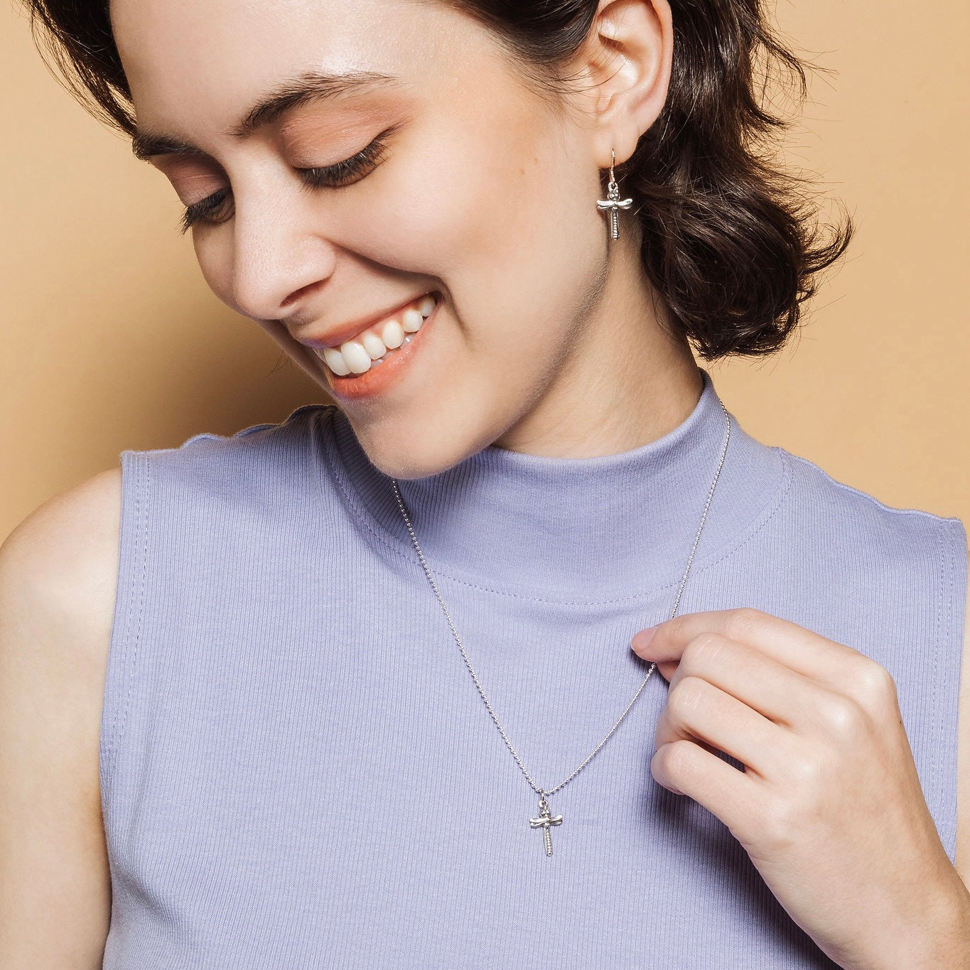Woman wearing petite dragonfly cross pendant necklace and earrings set