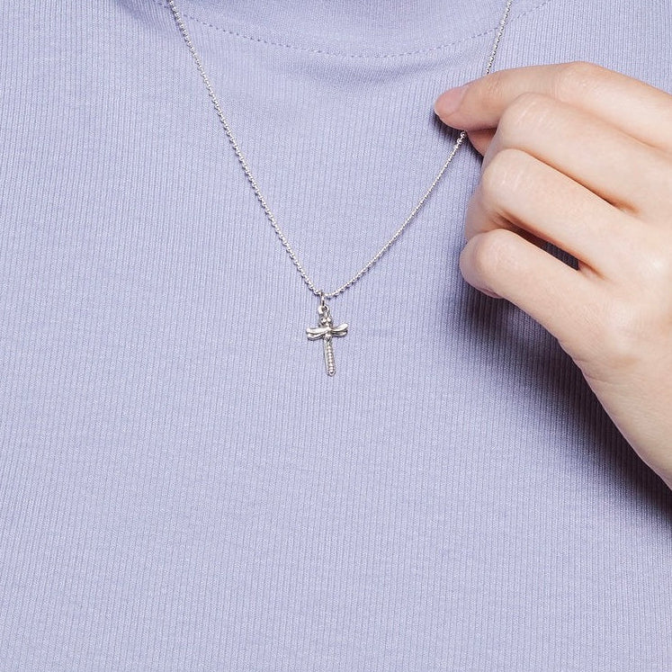 Close-up of petite dragonfly cross pendant necklace worn