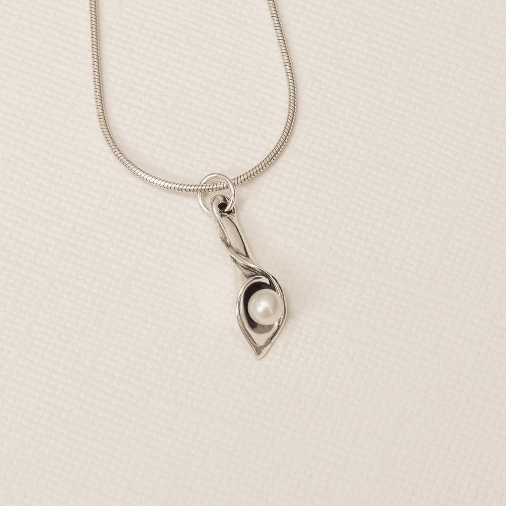 Sterling silver calla lily pearl pendant with freshwater pearl flat lay close up detail 