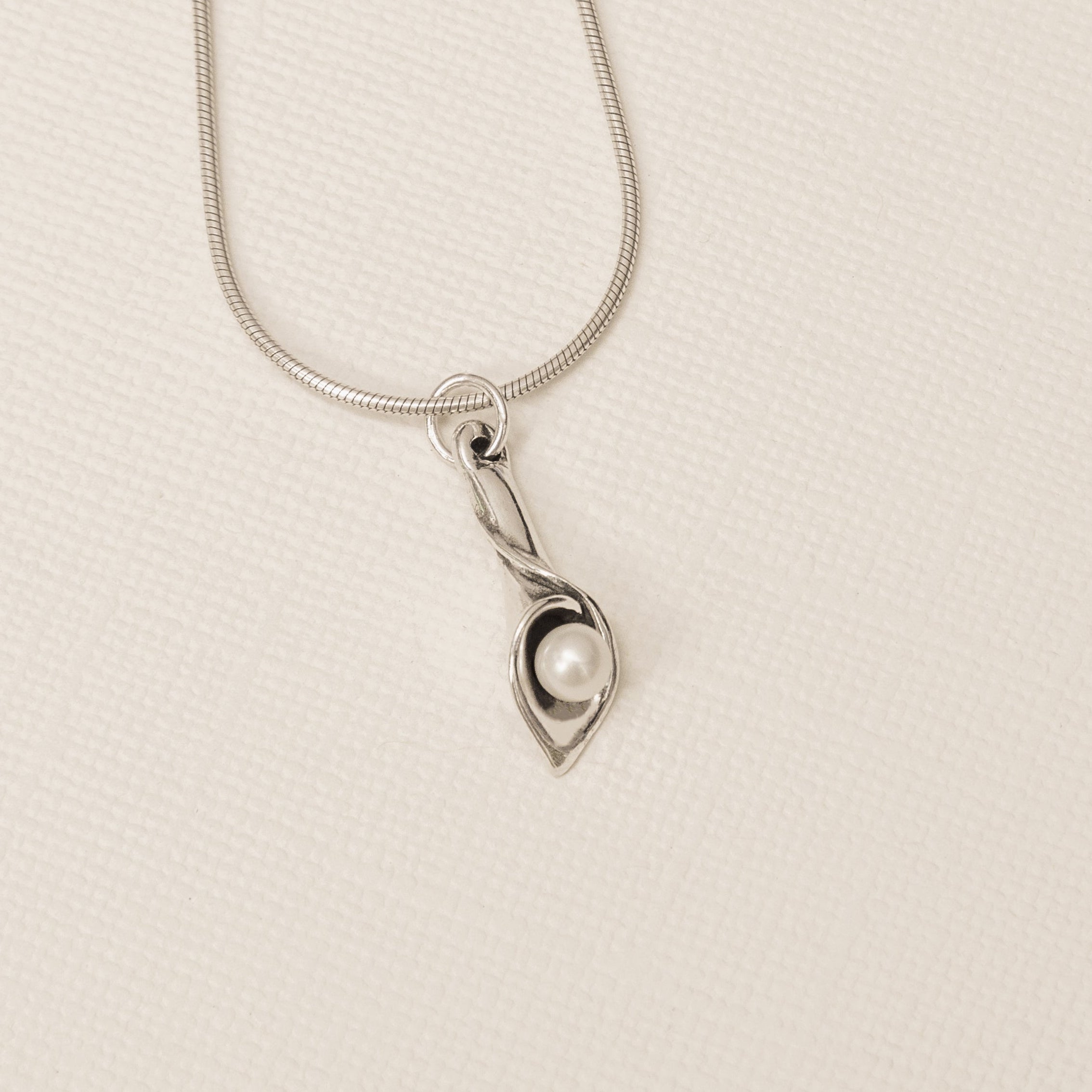 Sterling silver calla lily pearl pendant with freshwater pearl flat lay close up detail 