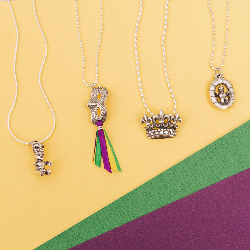 Baby in King Cake Mardi Gras necklace featuring purple green and gold New Orleans colors
