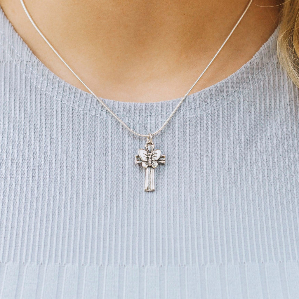Close-up of butterfly cross pendant necklace worn