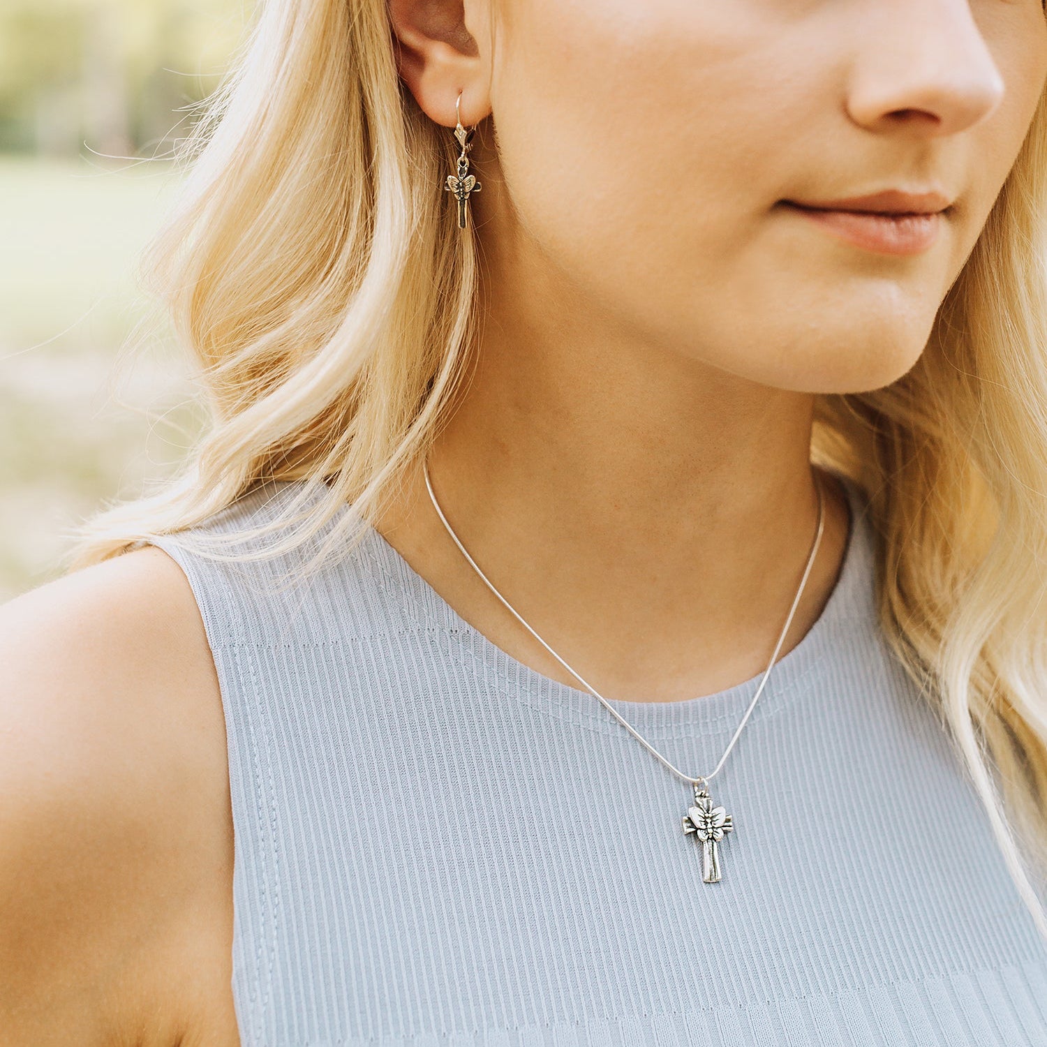 Woman wearing butterfly cross pendant necklace