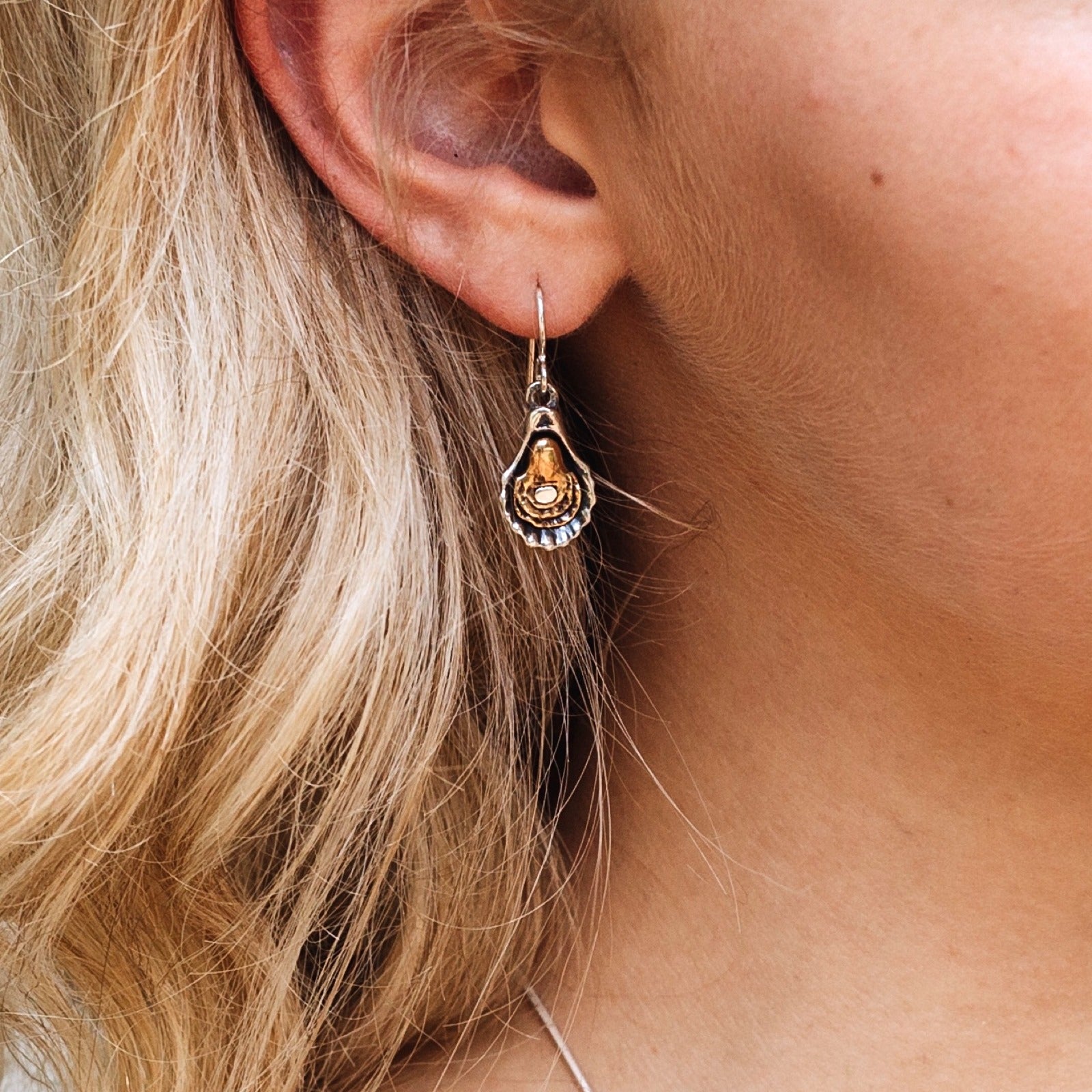 woman wearing charbroiled oyster earrings silver and bronze