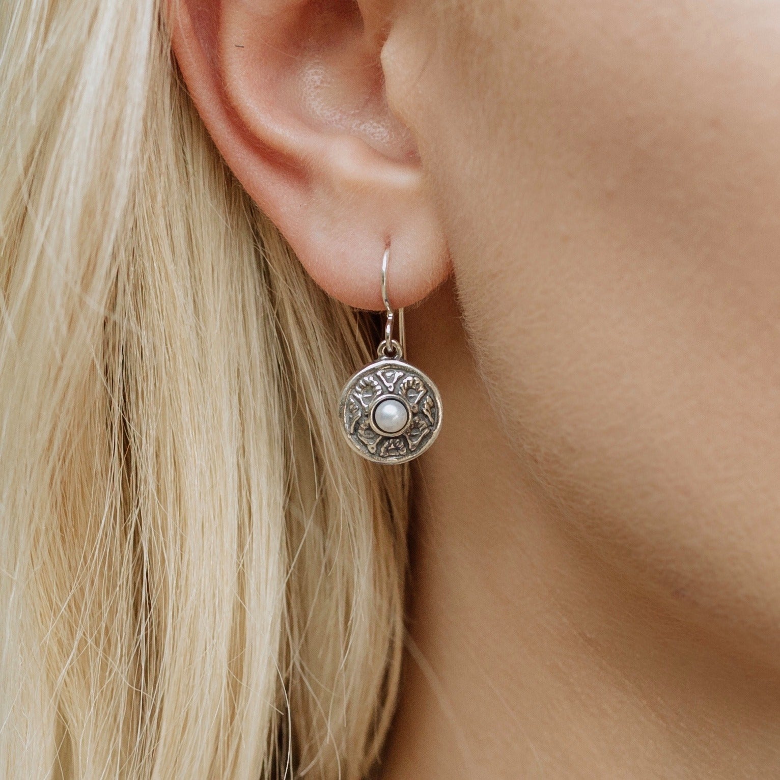 coquille oyster pearl earrings worn on ear showing delicate circular shell design and center pearl