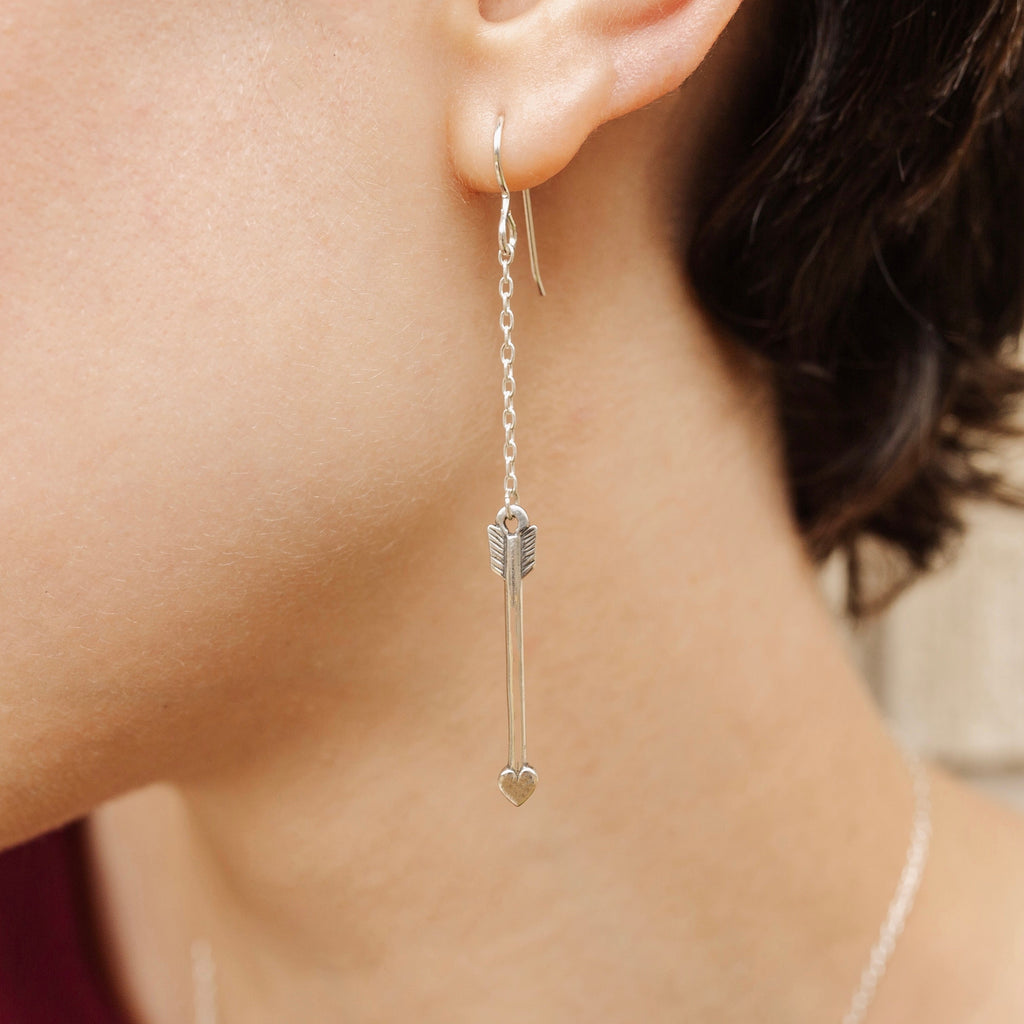 Woman wearing sterling silver Cupid arrow drop chain earrings with elegant movement