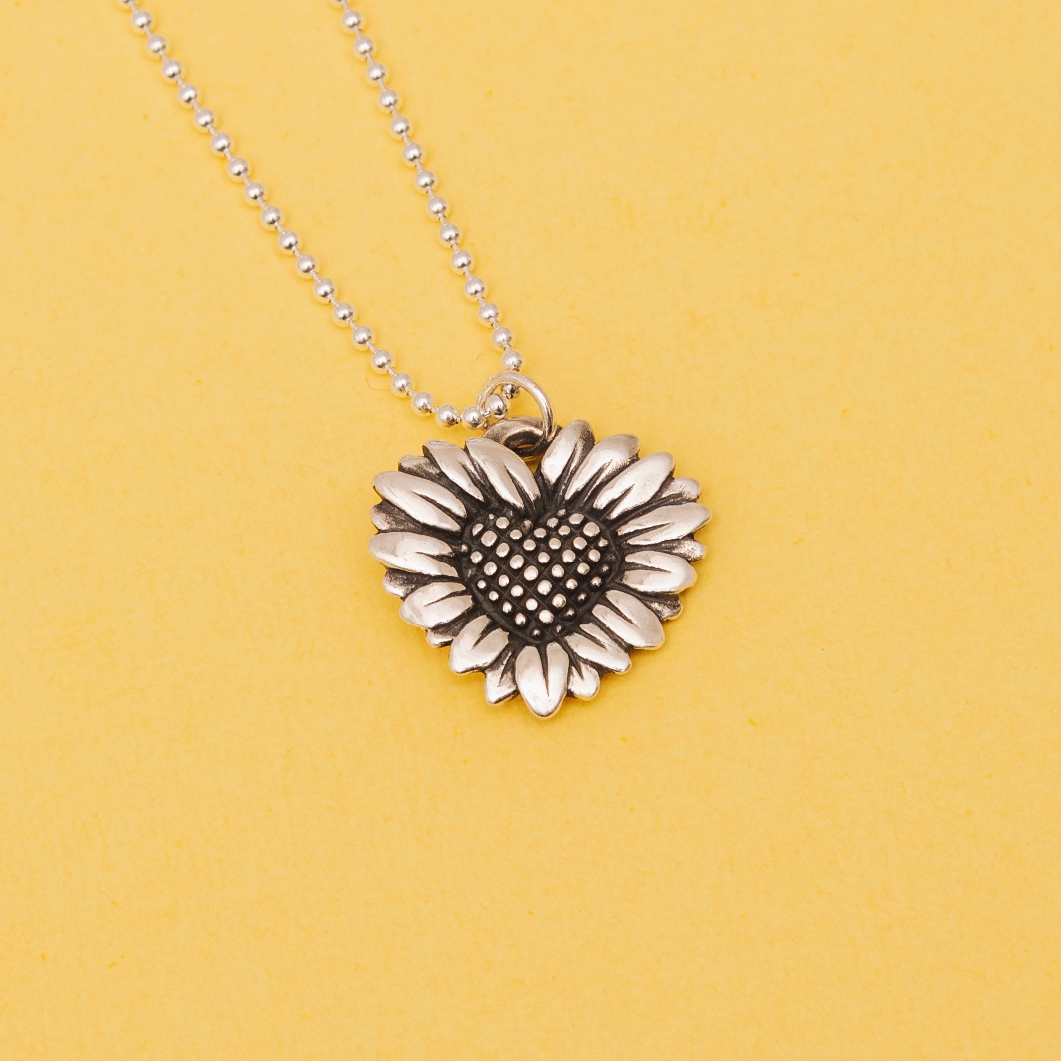 daisy heart pendant on yellow background showing detail