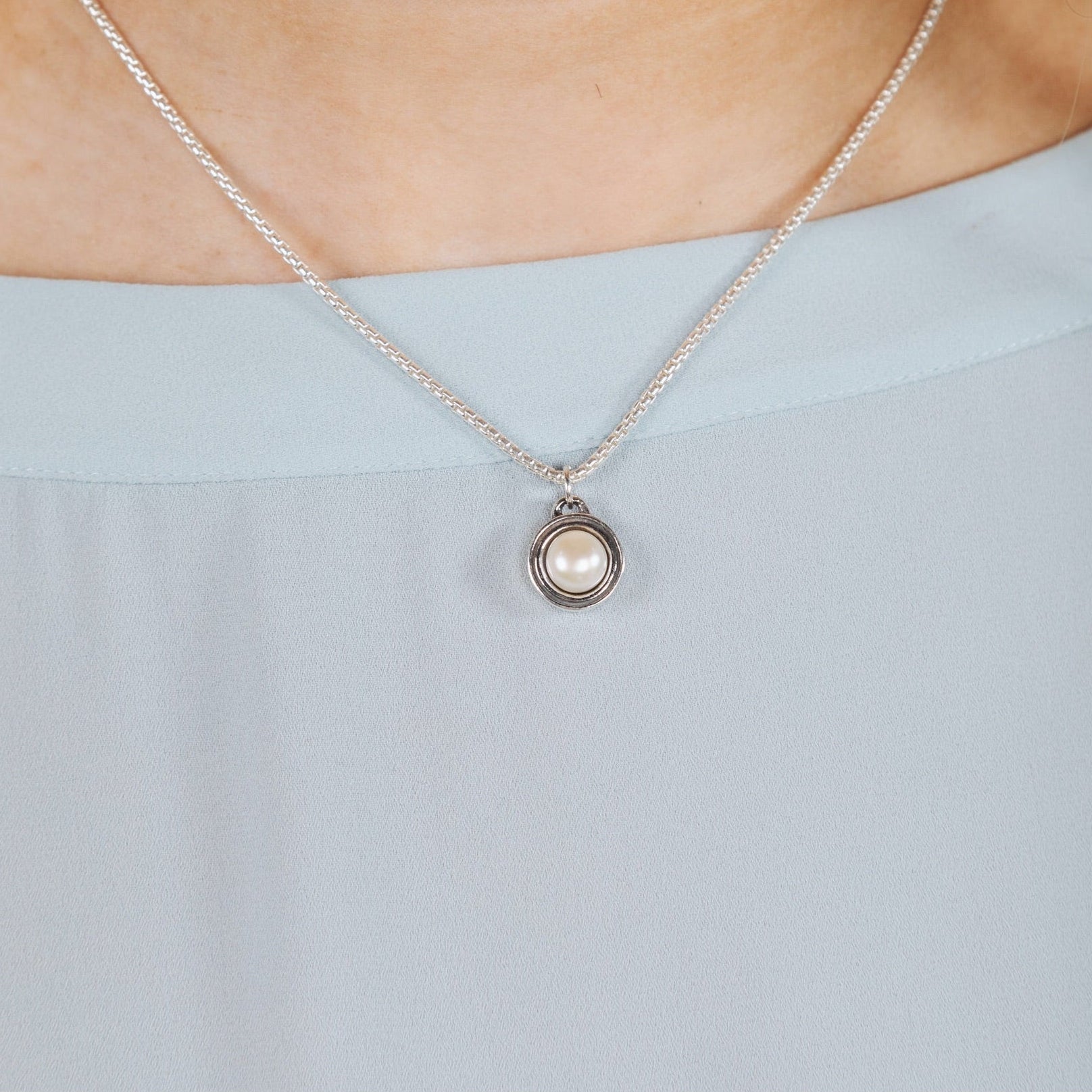 Woman wearing the Deceaux Pearl Pendant inspired by Art Deco design.