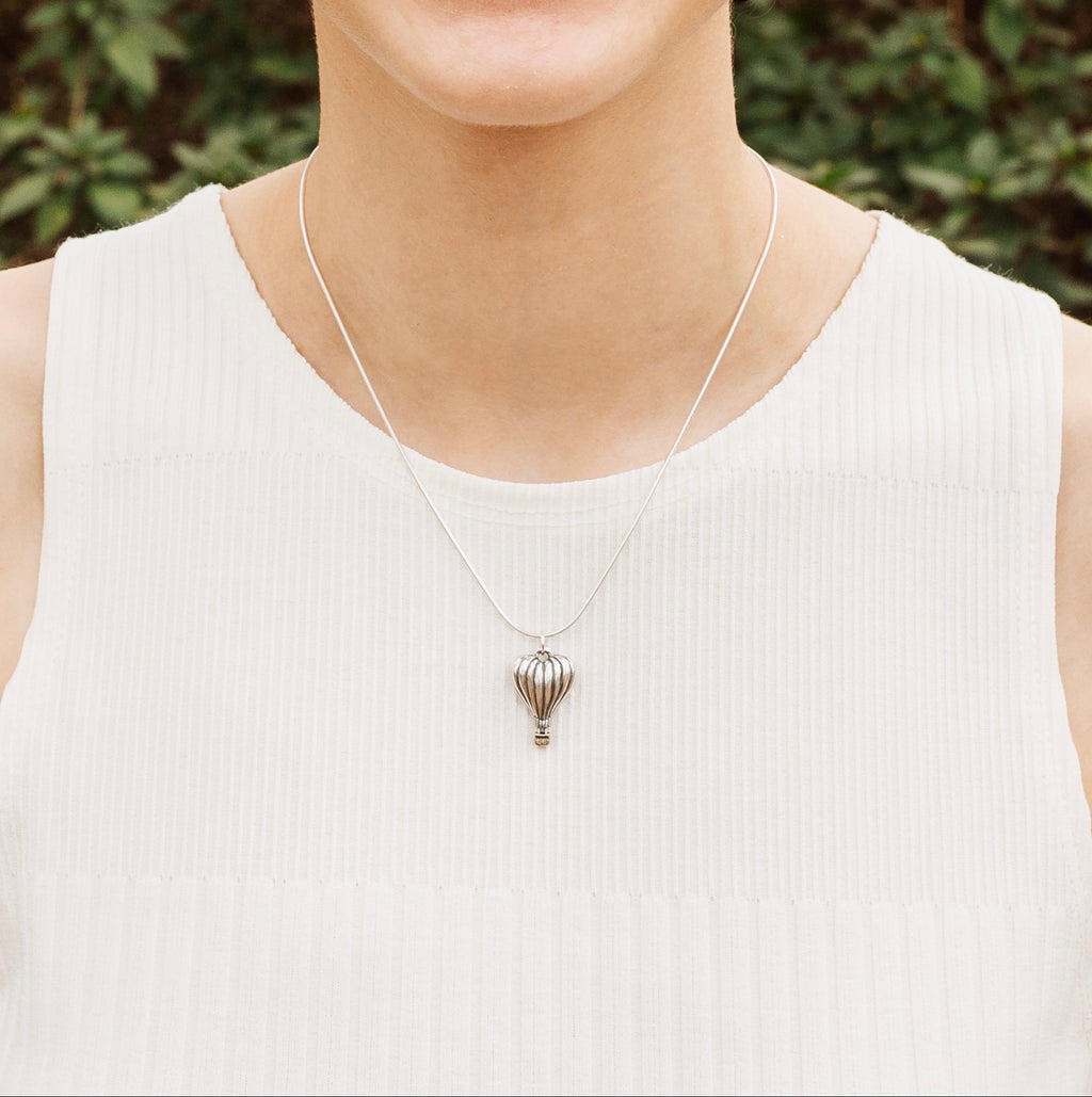 Woman wearing heart hot air balloon pendant necklace in sterling silver and bronze
