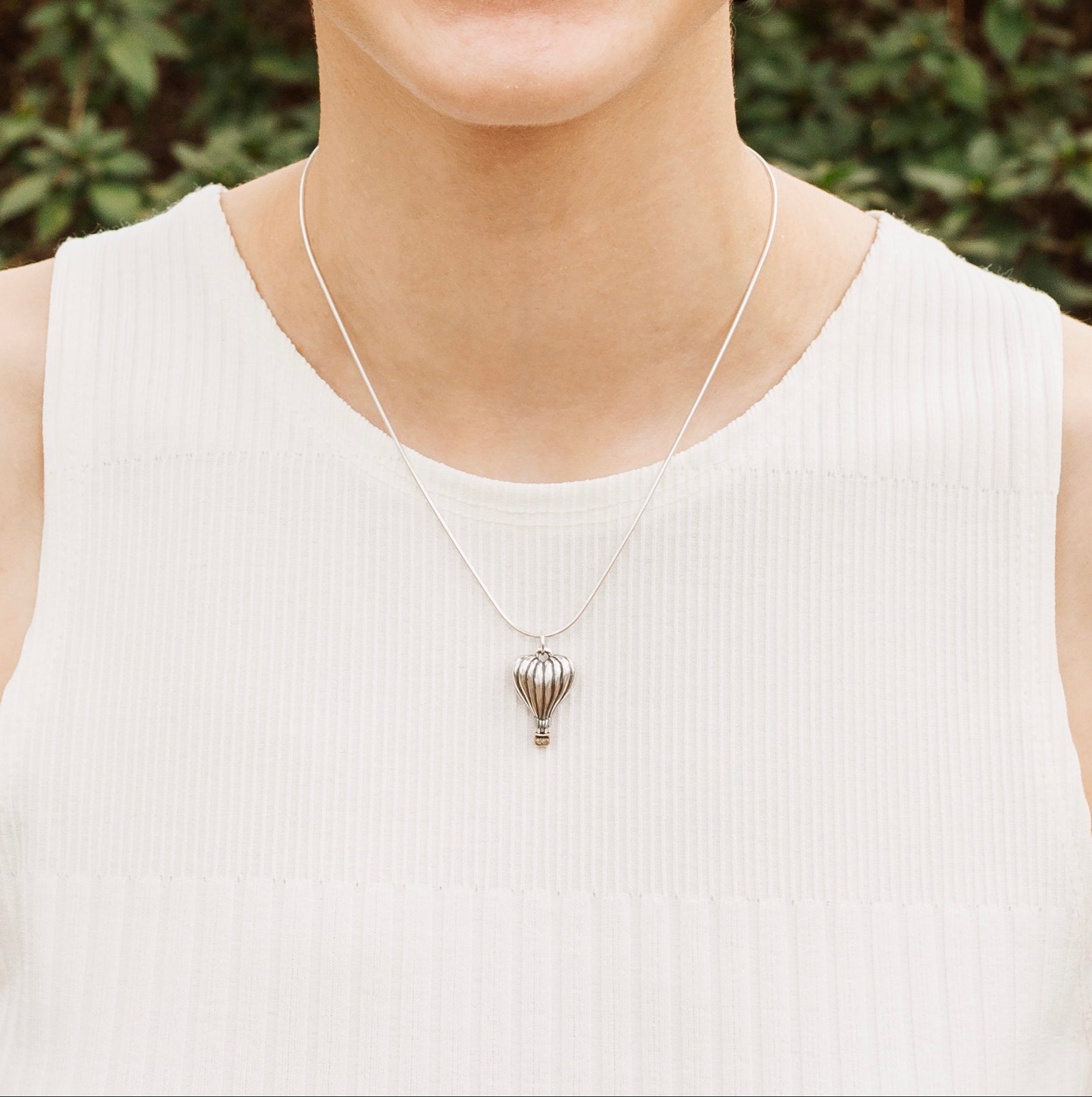 Woman wearing heart hot air balloon pendant necklace in sterling silver and bronze