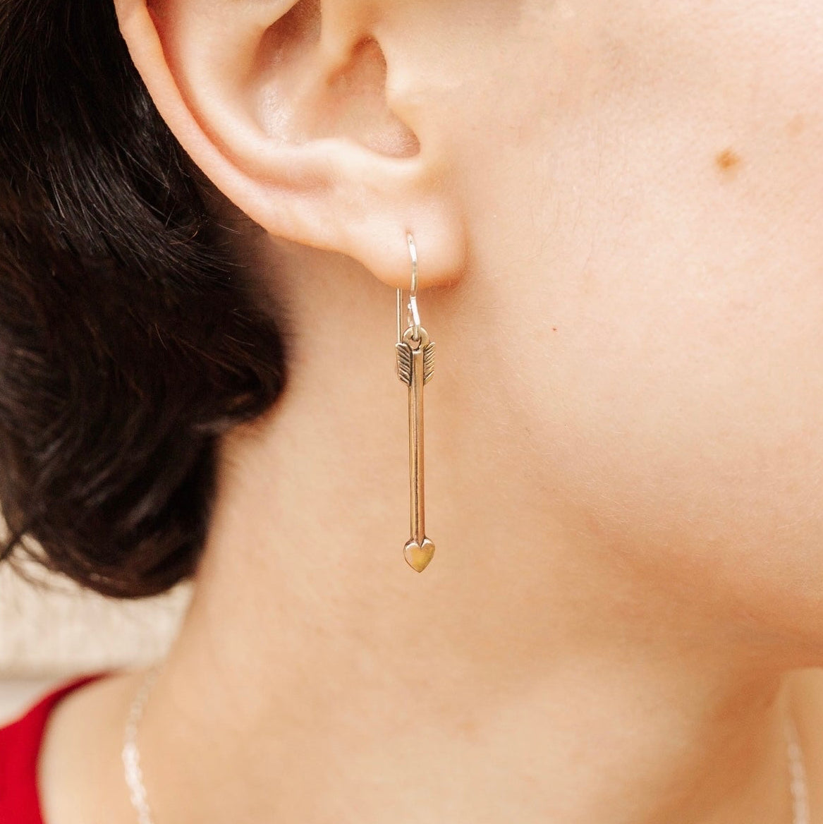 Woman wearing Lovestruck bronze arrow earrings with delicate dangling design