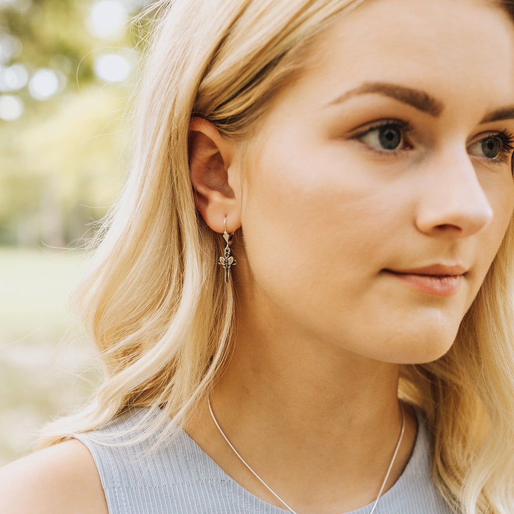 close-up of petite butterfly cross earrings worn, dainty faith-inspired jewelry