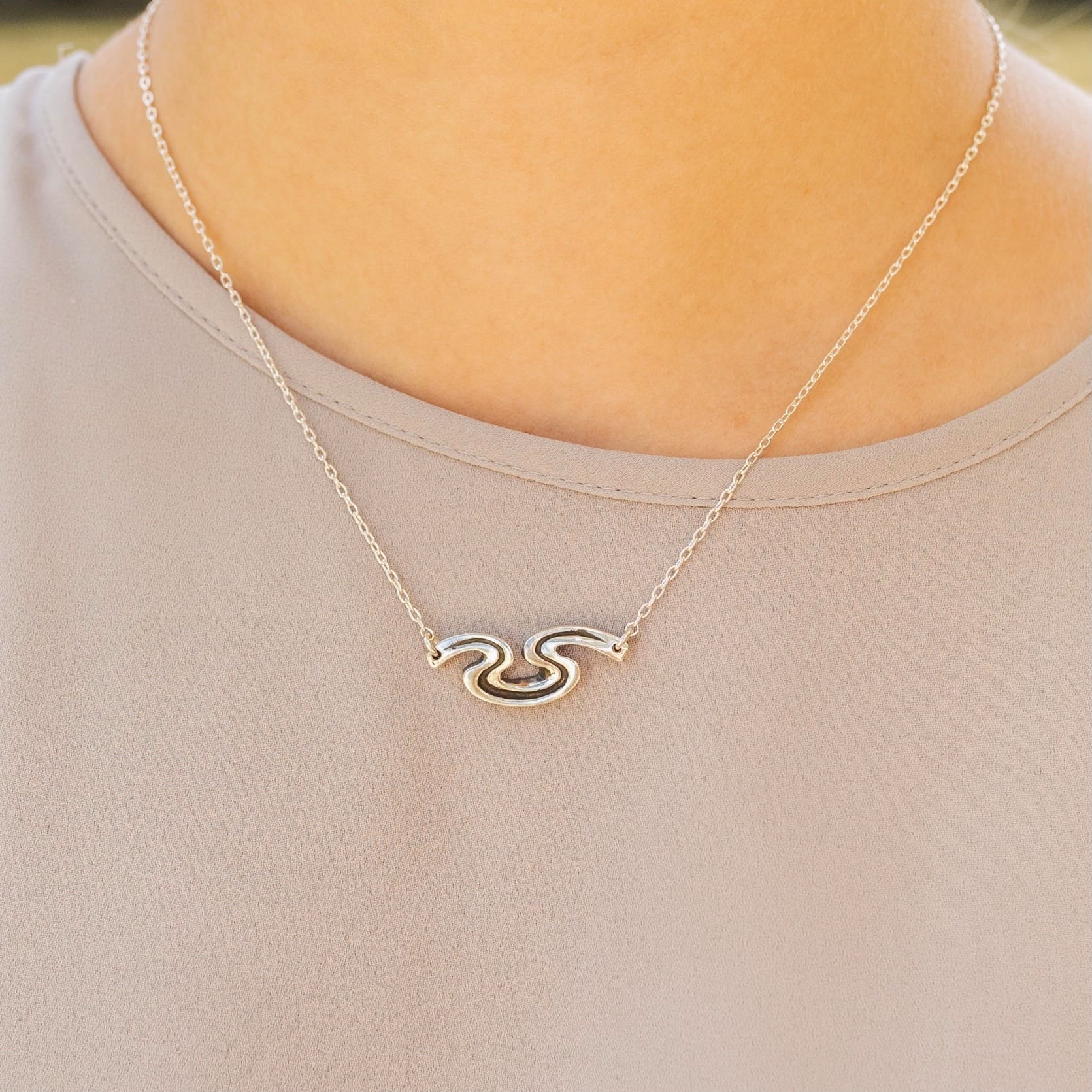 Model wearing Riverbend sterling silver necklace inspired by the Crescent City riverbend.